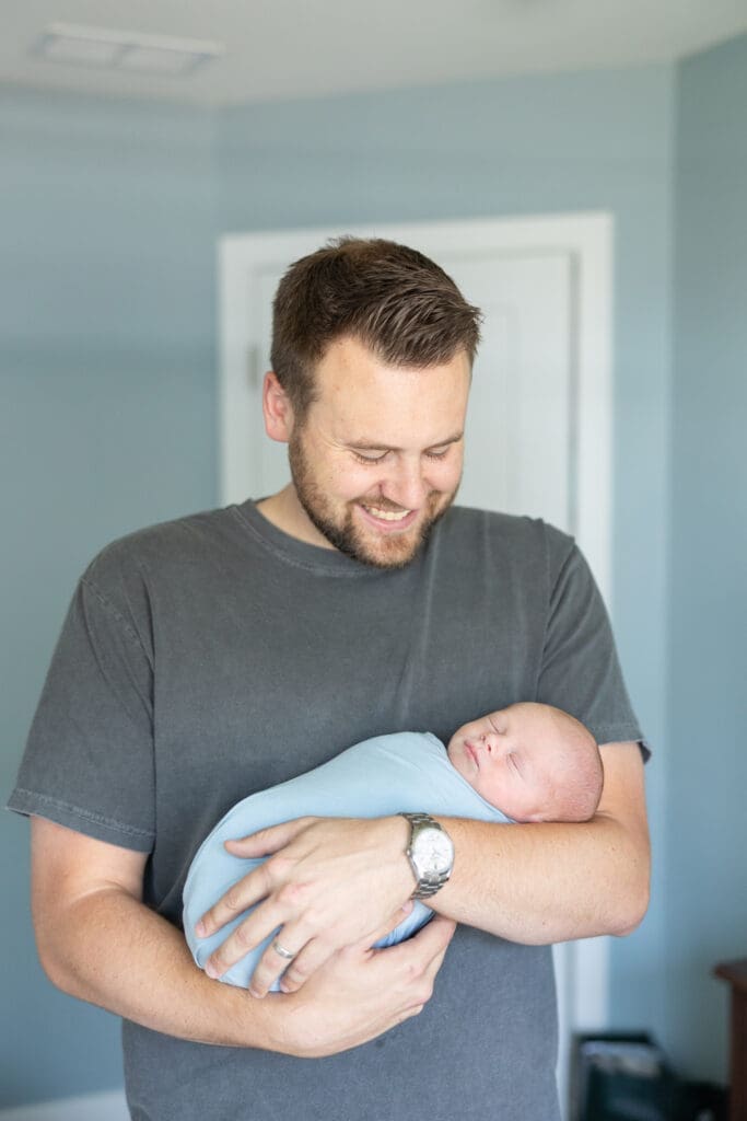 Father cuddling newborn baby boy at a lifestyle photography session.