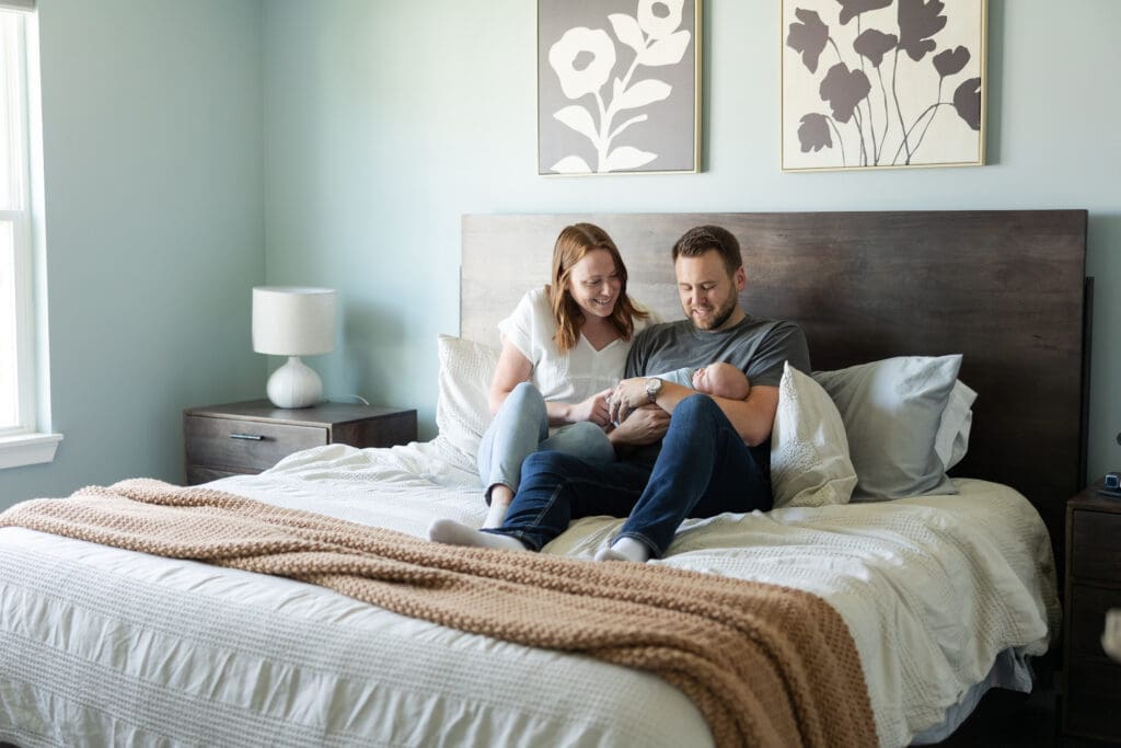 Cozy at home newborn session with newborn baby in the arms of parents in their room.