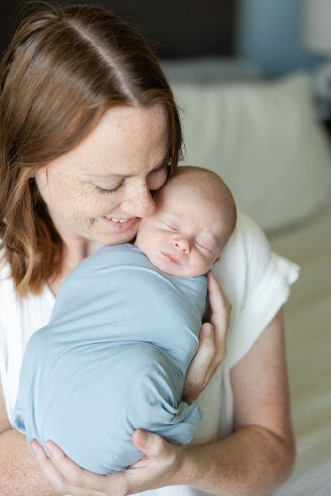 Capturing both newborn baby boy and mother face to face during a photo shoot at home.