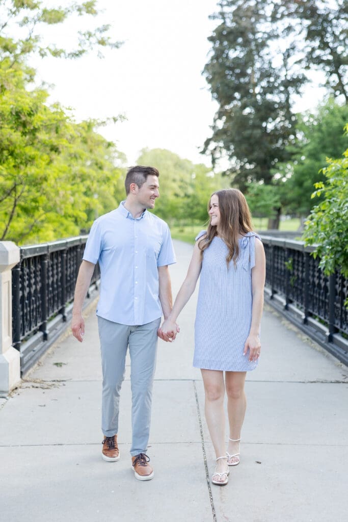 Newly engaged couuple wallking over a bridge hand in hand.