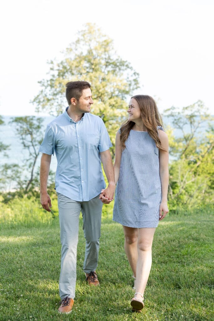 Engaged couple walking hand in hand after their engagement with views from Lake Michigan in the background.