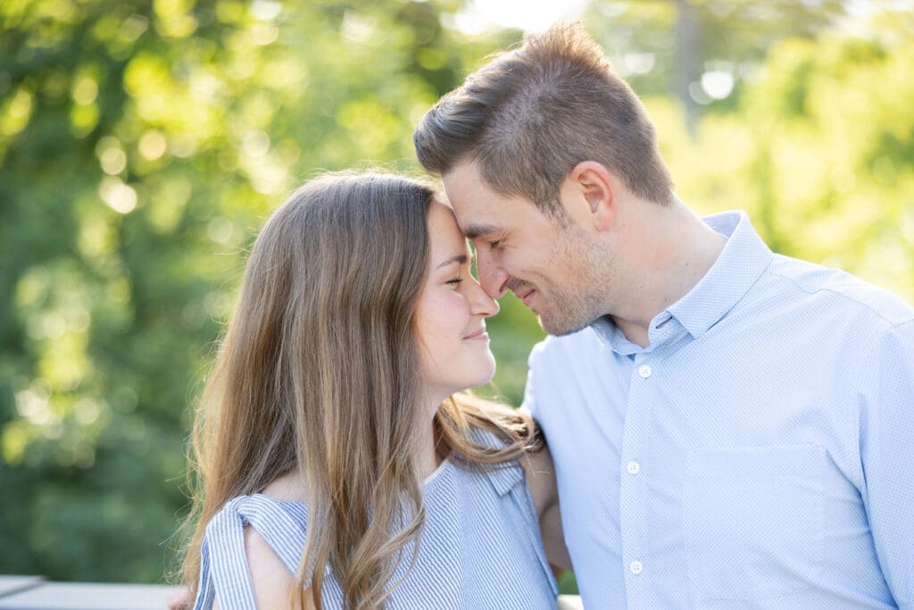 Up close photo with a happily engaged man and woman face to face with their noses touching and eyes closed.