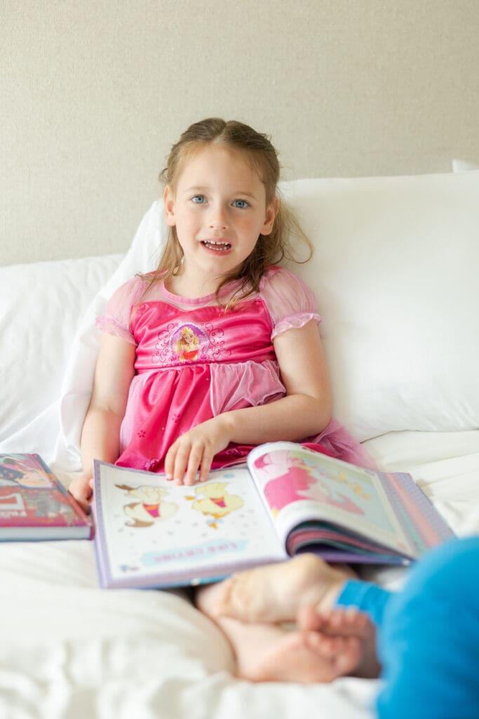 Young girl reading book on the bed.