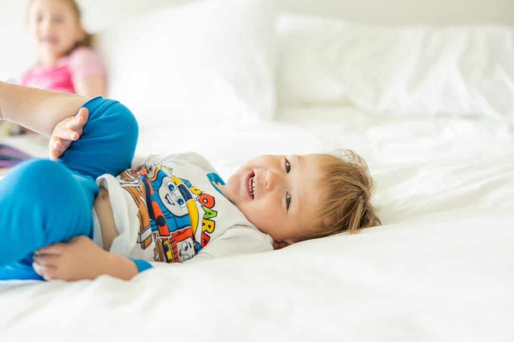 Young boy smiling and playing with the photographer while taking pictures during a relaxed session.