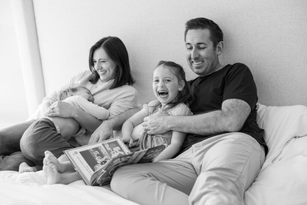 Family reading books together on the bed. 