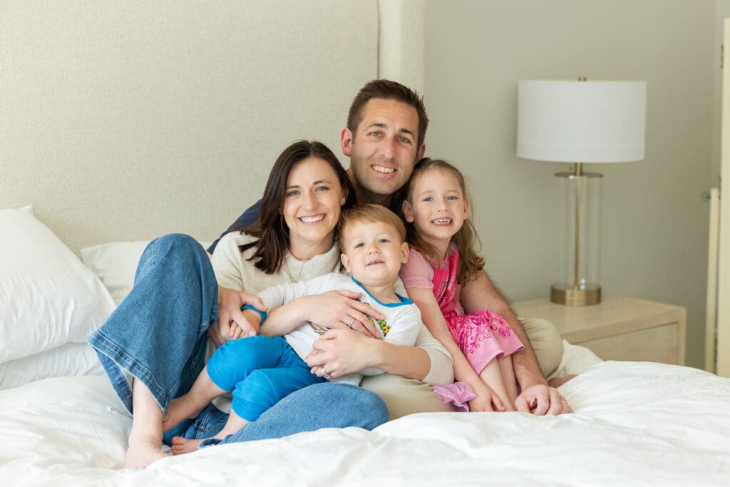 Beautiful family with their young son and daughter all smiling and hugging during a relaxed at home photography session.