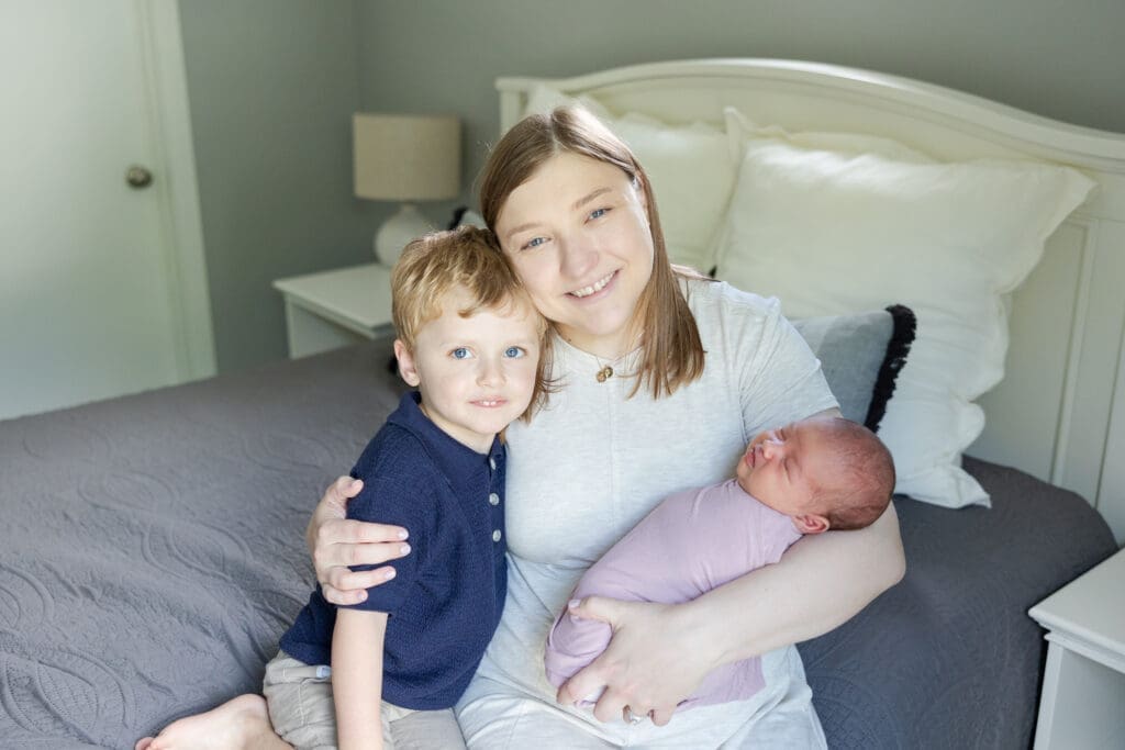 A mother with her toddler son and newborn baby girl during a photo shoot at home.