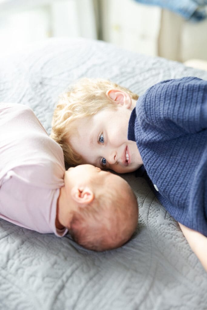 A sweet older brother looking endearingly at his new baby sister.