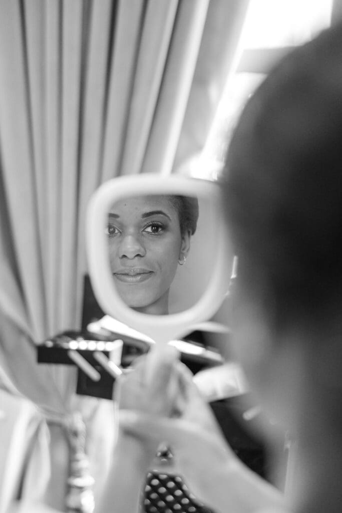 Bride looking into a mirror after her makeup is done. 