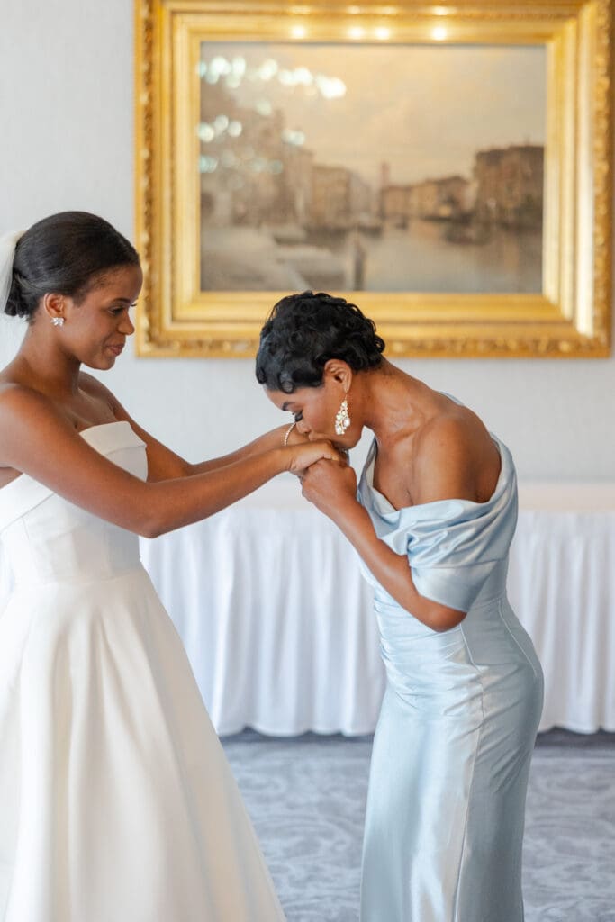 Mother kissing her daughter on the hands on her wedding day.