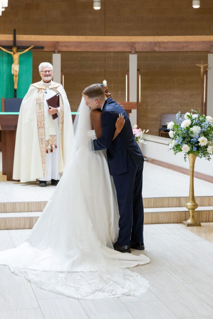 Bride and groom embracing when they finally reach one another down the isle. 