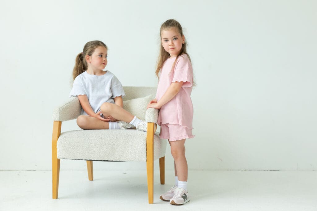One girl sitting on a chair while another girl standing near