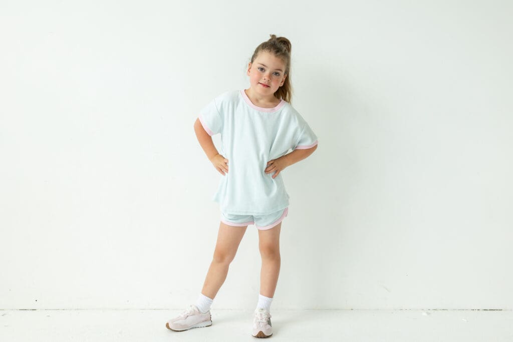 Girl with hands on her hips smiling at the camera.