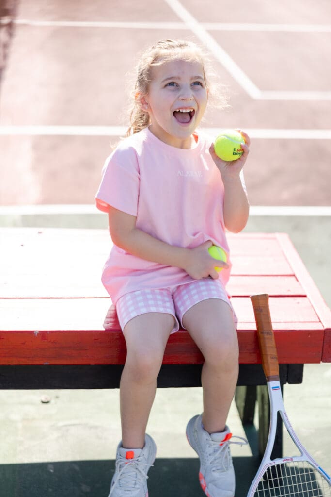 Girl smiling up at the camera and holding tennis balls