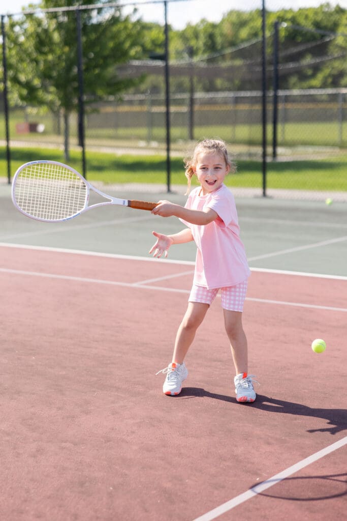 Girl hitting a tennis ball on the tennis court during a commerical photo shoot.