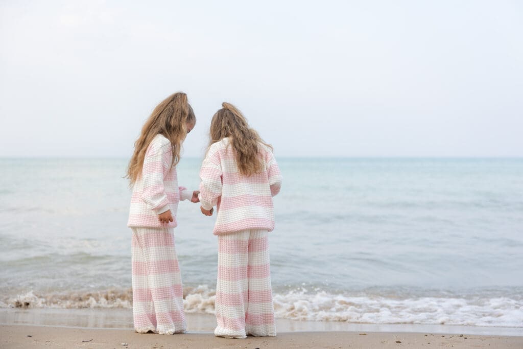 Two young girls looking at shells on the beach