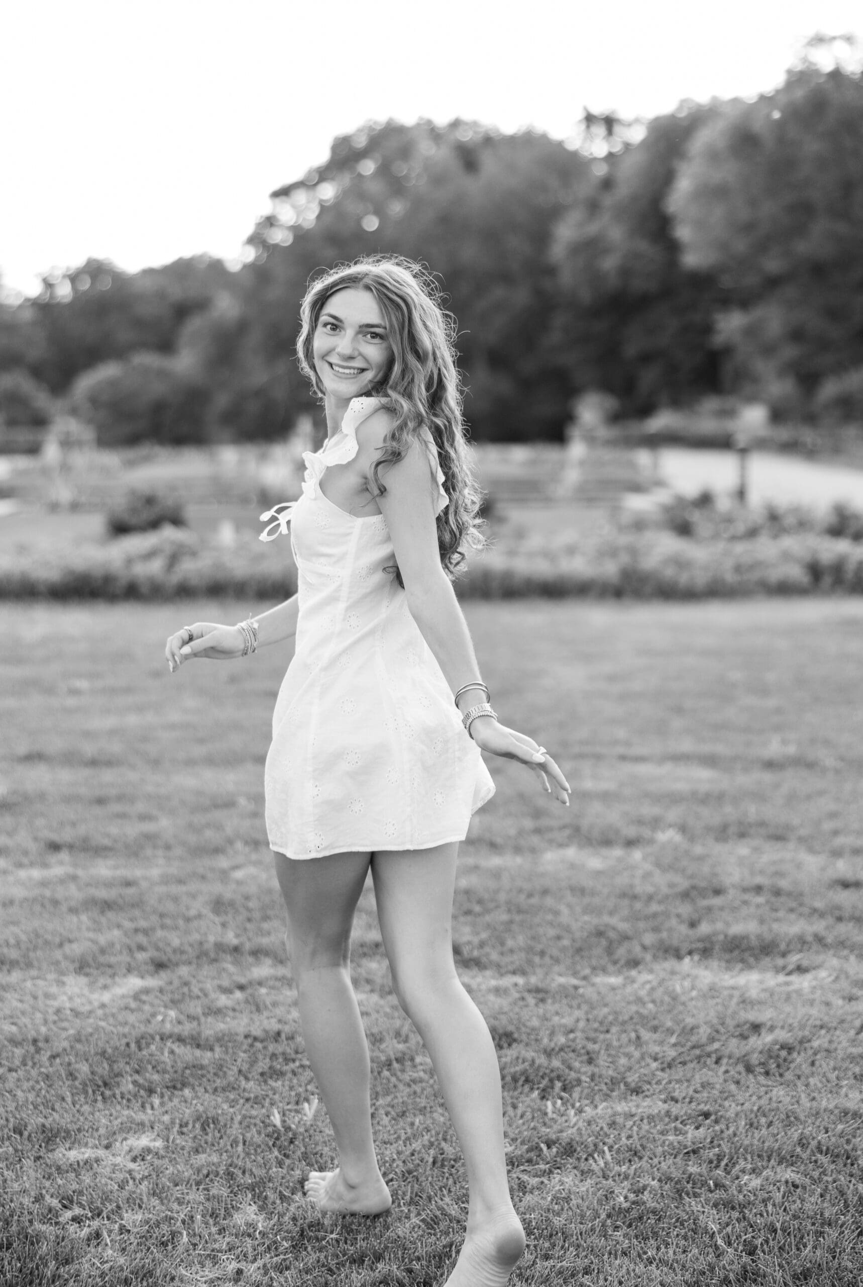 Girl running in a white dress looking back at the camera during her senior session. 