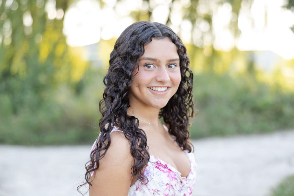 A close up shot of a girl with curly brown hair, smiling during her senior session in Milwaukee.