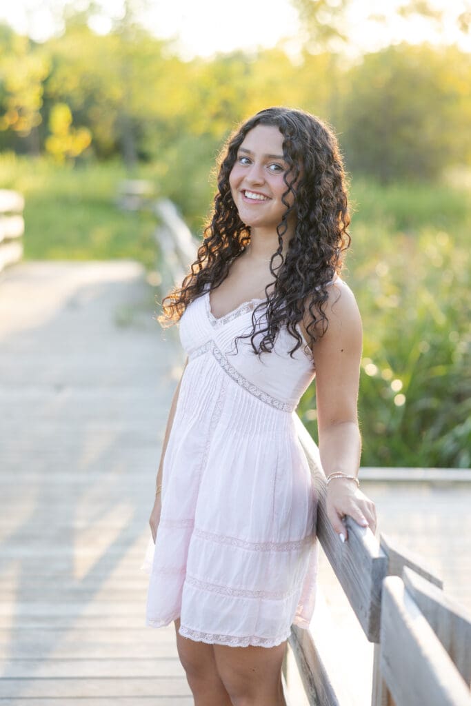 A girl on a bridge with lots of greenery around her.