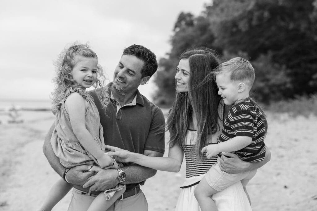 A beautiful lifestyle family photography session on the beach, parents playfully holding children. 
