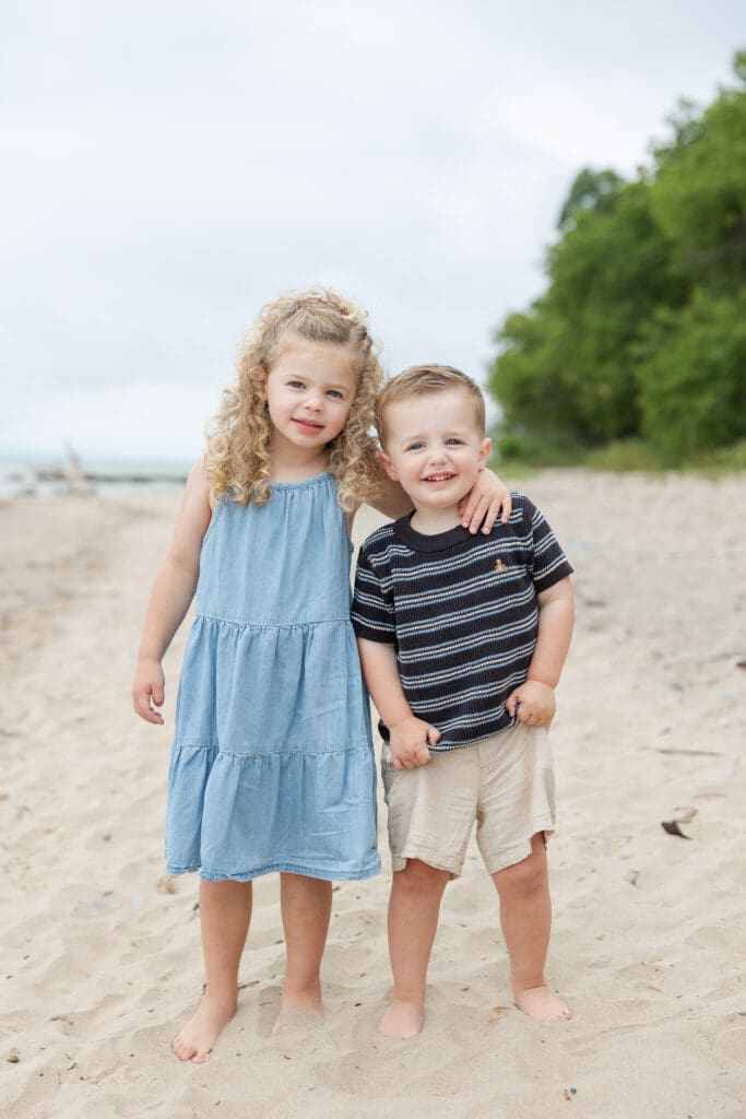 Young brother and sister hug and smile at the camera during their family session at Doctors Park in Fox Point, Milwaukee. 