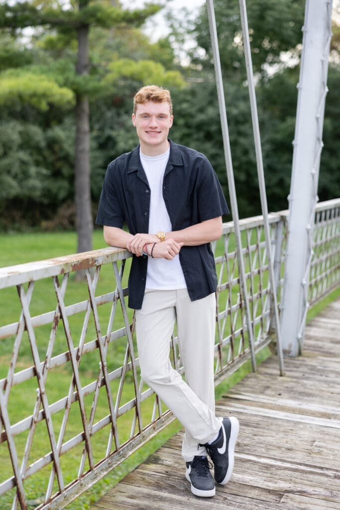 A young man leaning on a fence.
