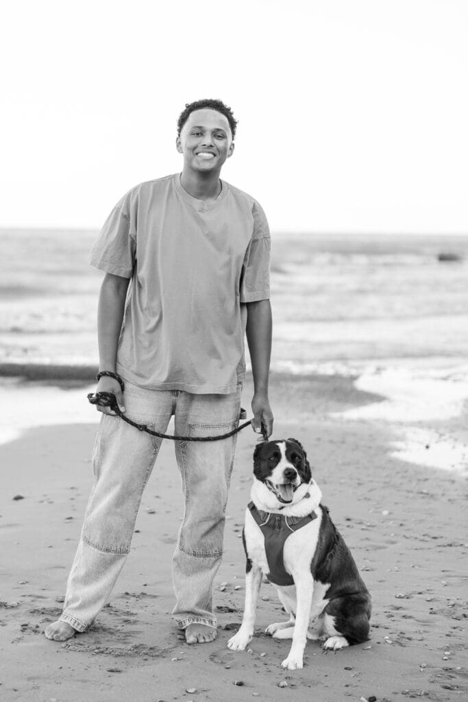 Boy holding his dog by the leash on the beach 