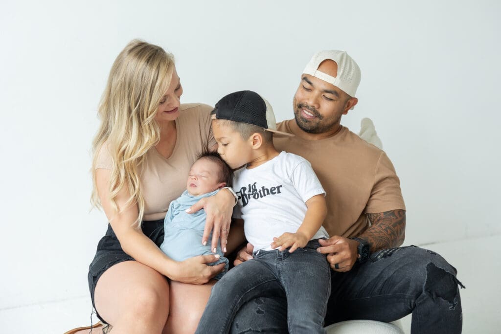 Big brother kissing newborn baby during Milwaukee studio session